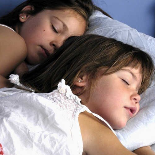 Dos niñas durmiendo en una cama.