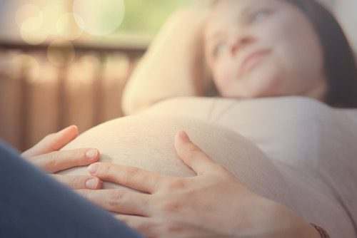 Una mujer embarazada está acostada en un sofá con las manos en el estómago y experimenta apnea del sueño.