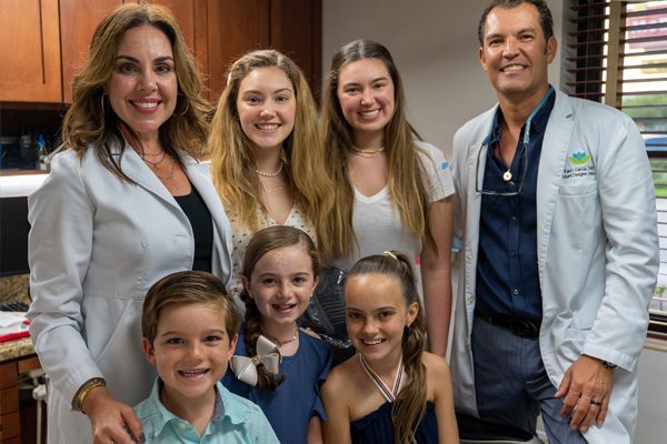 Acerca de nuestra práctica, una familia posando para una foto en un consultorio dental.