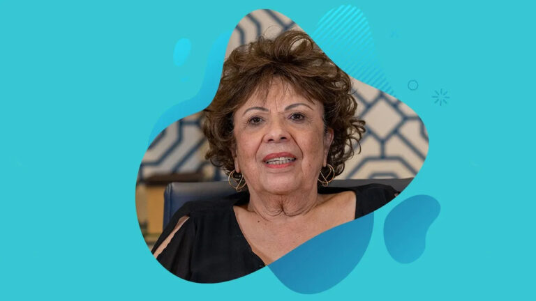 A woman with short, curly hair and hoop earrings is speaking against a blue geometric background, framed by abstract shapes, sharing her journey of smile transformation with Miami Designer Smiles.